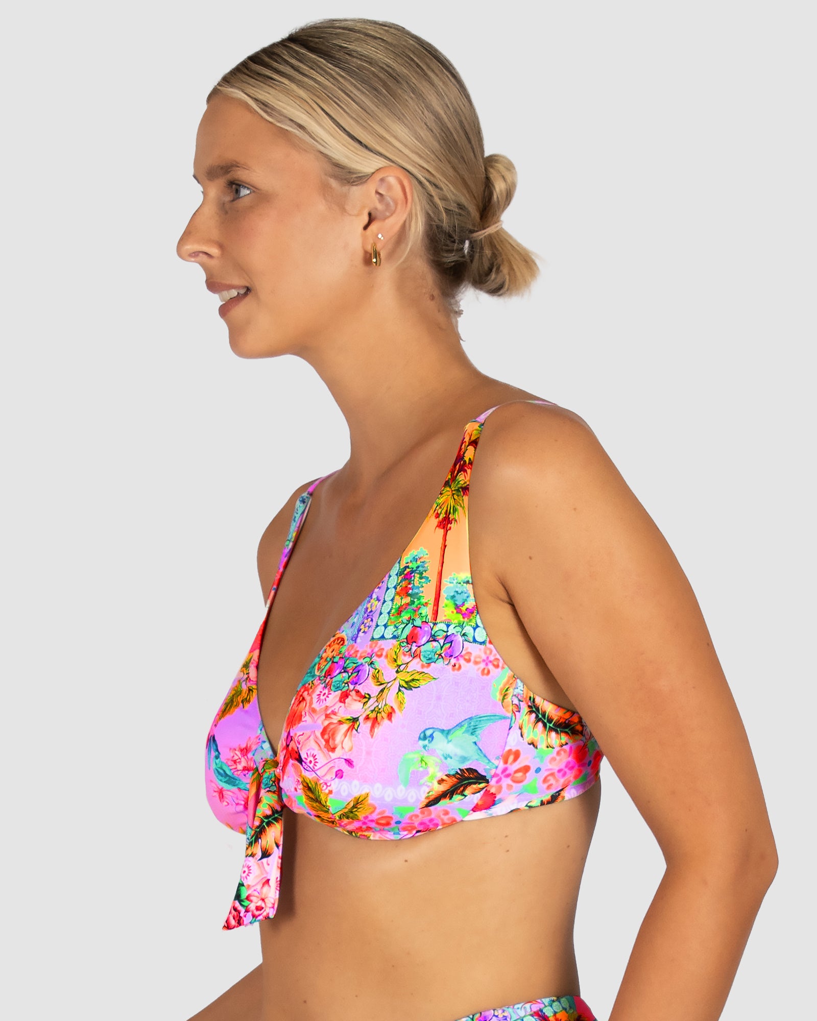 Woman wearing a colorful floral bikini against a plain background