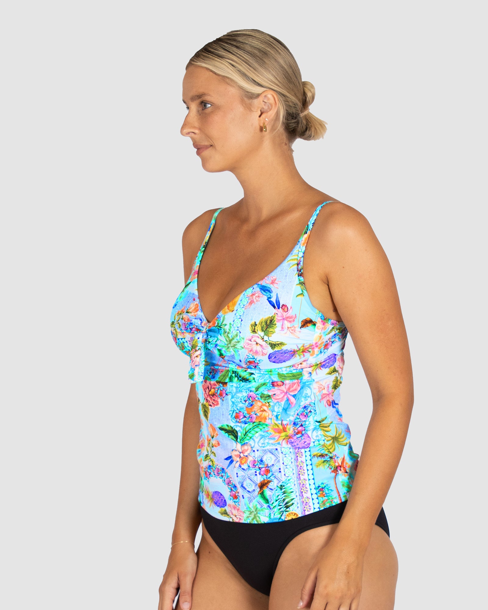 Woman wearing a colorful floral tankini top on a plain background