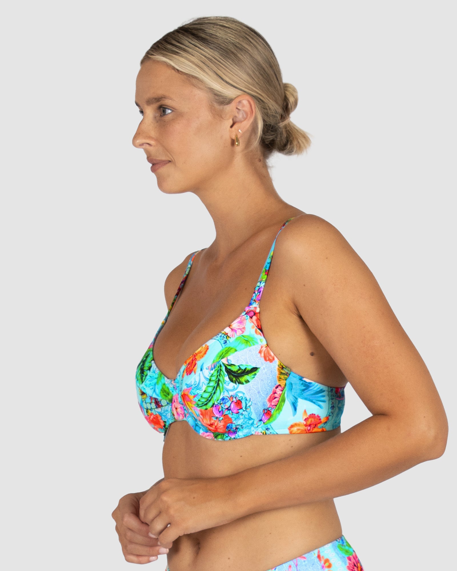 Woman wearing a colorful floral bikini against a white background