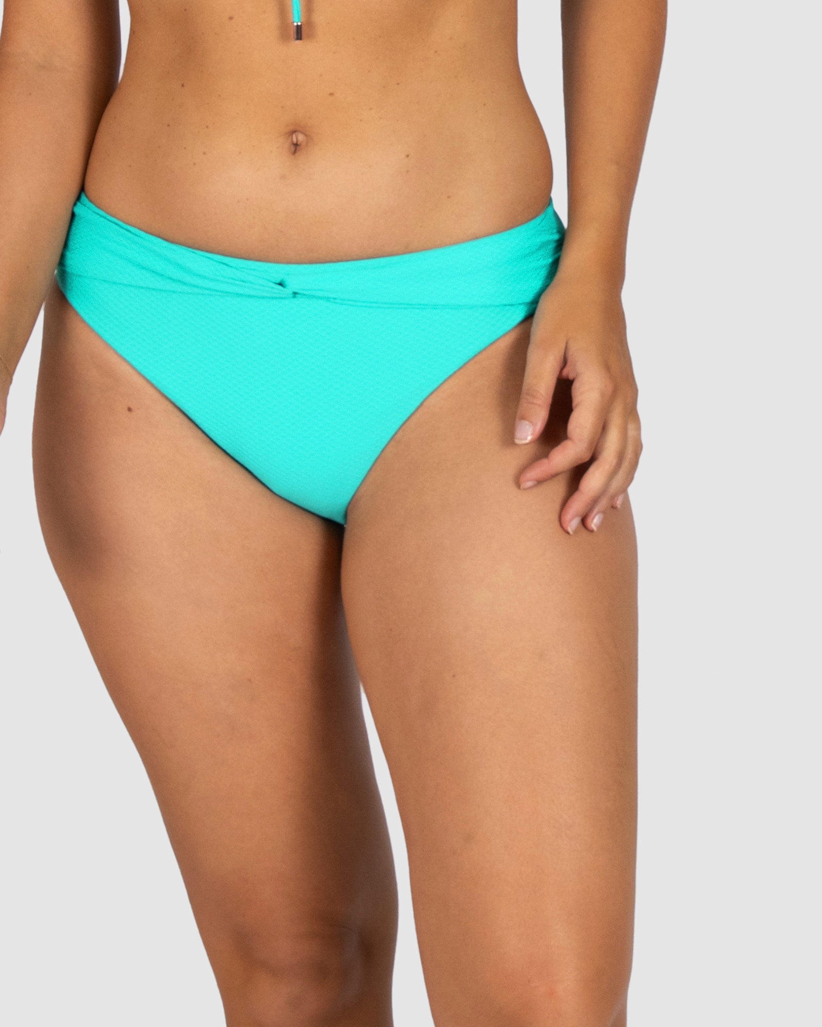 Baku is an Australian brand known for elegant swimwear. The Rococco Cabana Pant in Caribbean, a fresh blue-green shade, features a stylish twist belt, regular coverage, and mid-rise fit. Power mesh lining provides subtle tummy control in soft Spanish textured fabric.