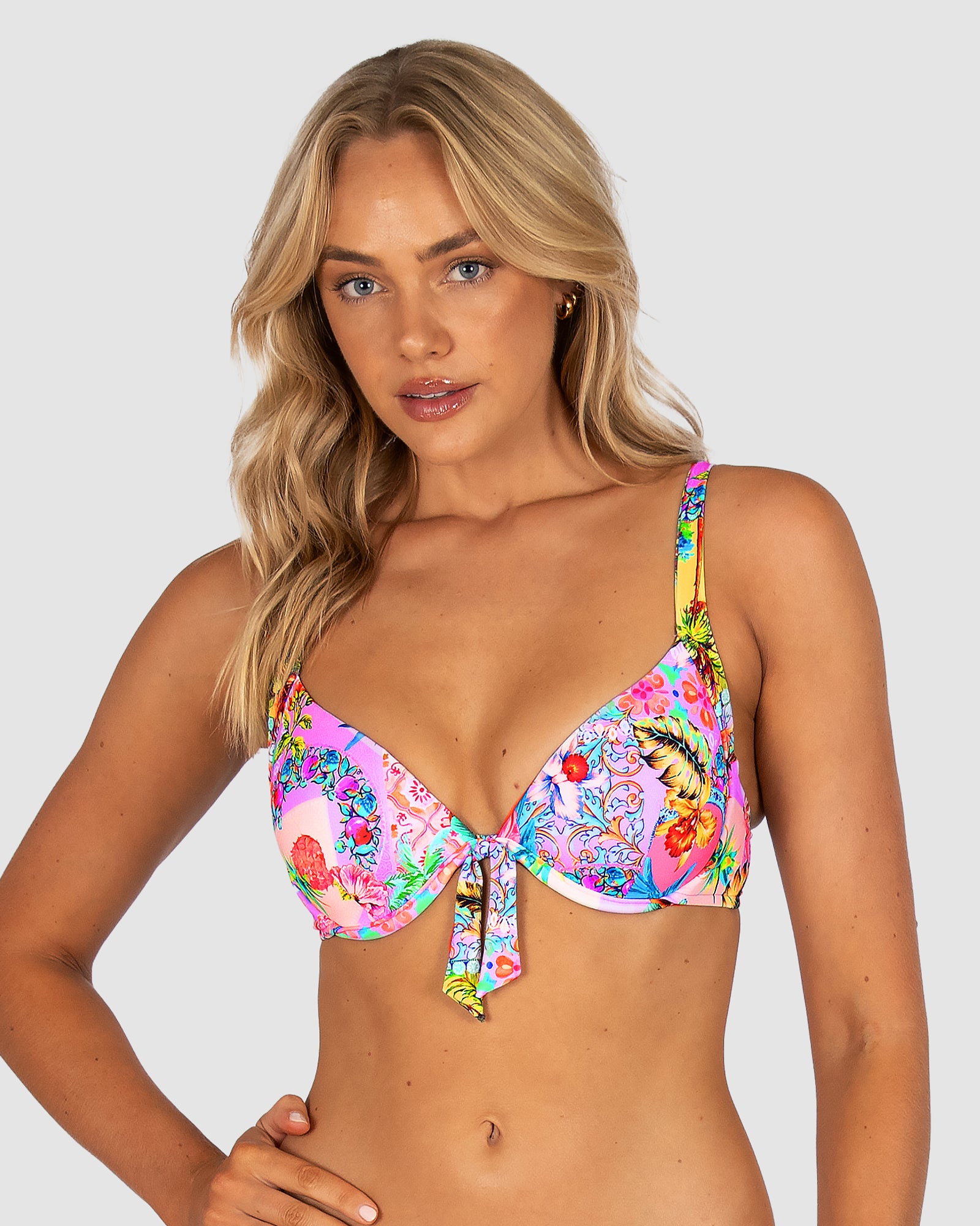 Woman wearing a colorful floral bikini top against a plain background