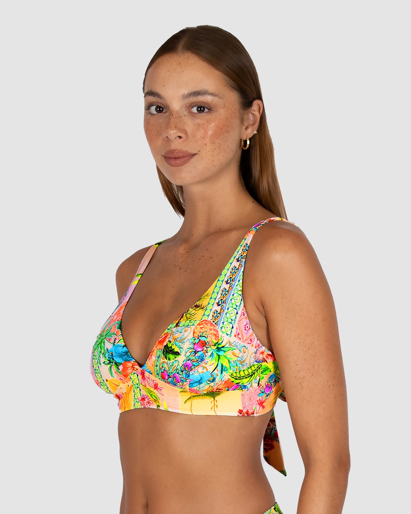 Woman wearing a colorful floral bikini top on a white background